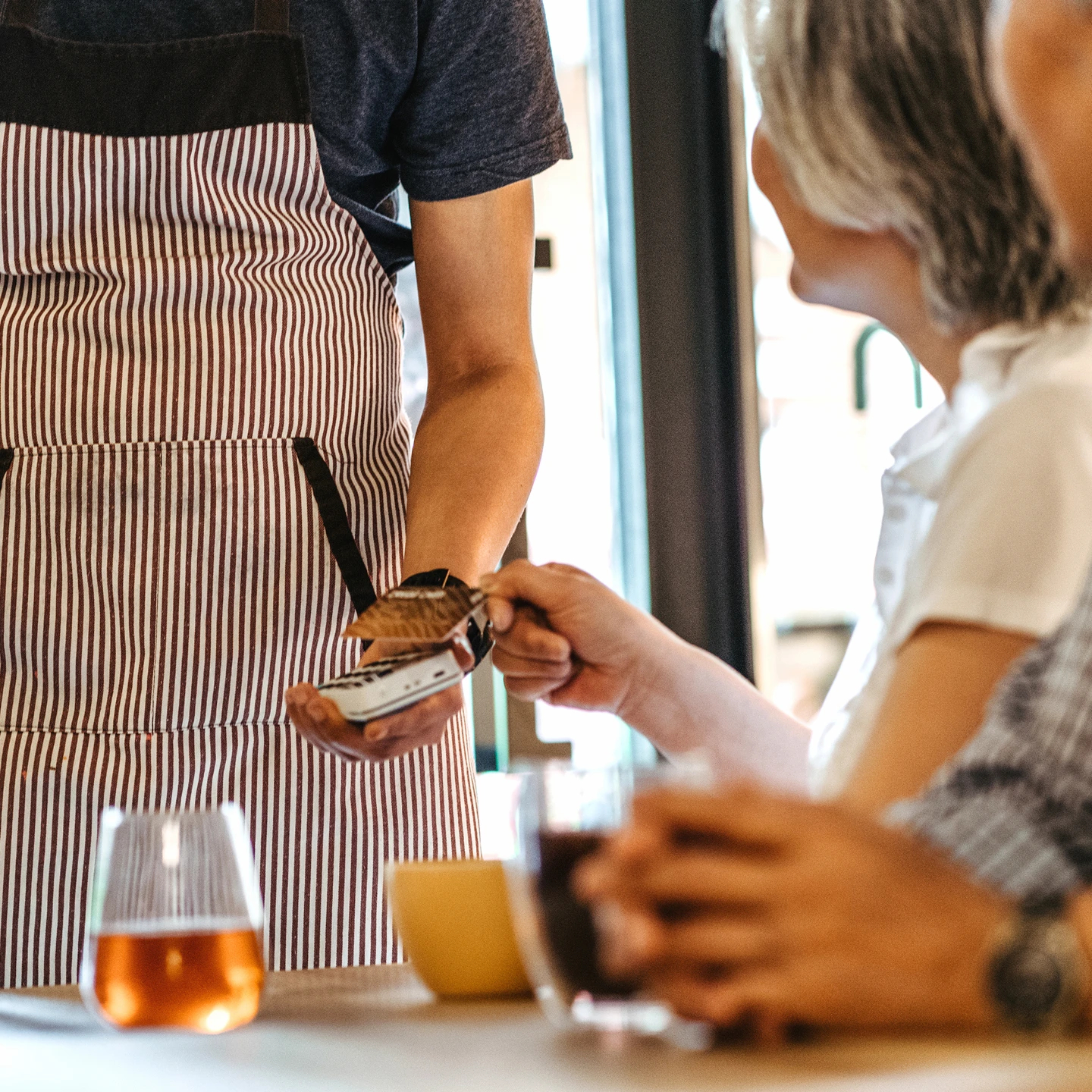 Un serveur de restaurant faisant payer une cliente avec sa machine POS.