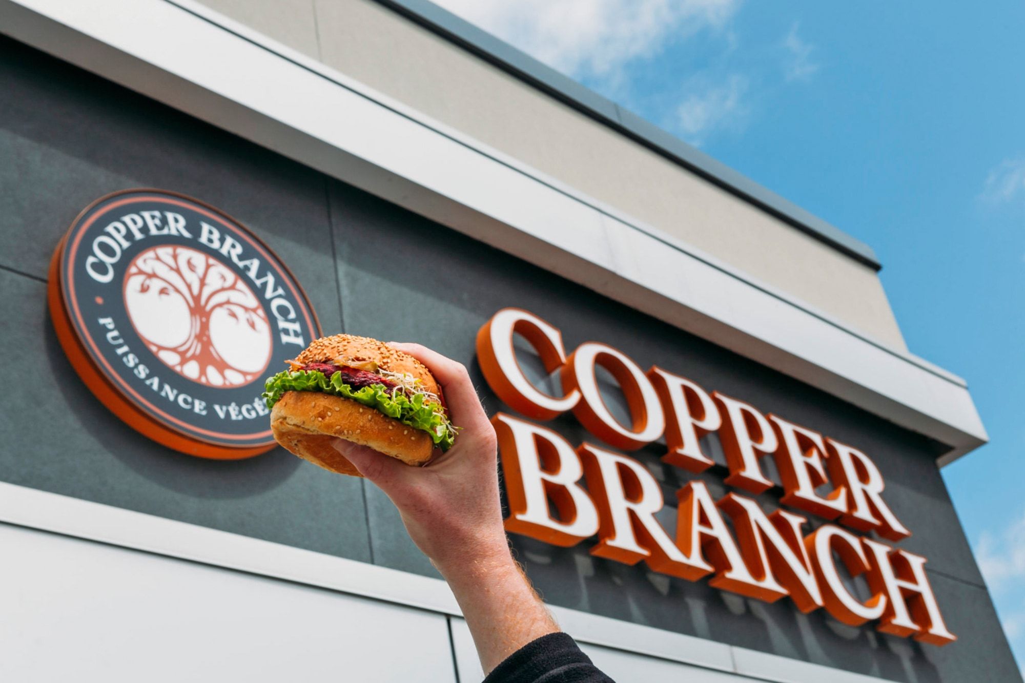 Burger signature de Cooper Branch tenu devant l'enseigne