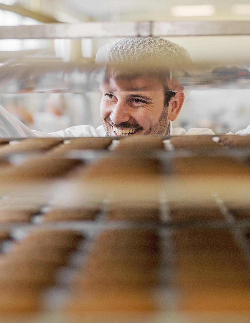 Portrait d'un pâtissier au travers d'un chariot de biscuits