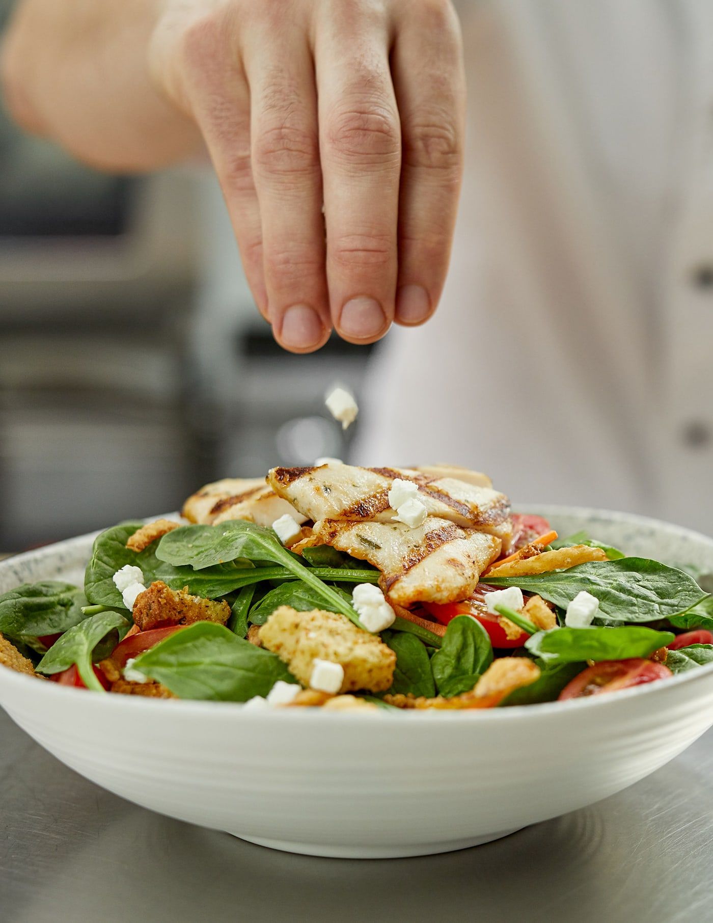 Chef saupoudrant un plat de salade de l'enseigne St-Hubert