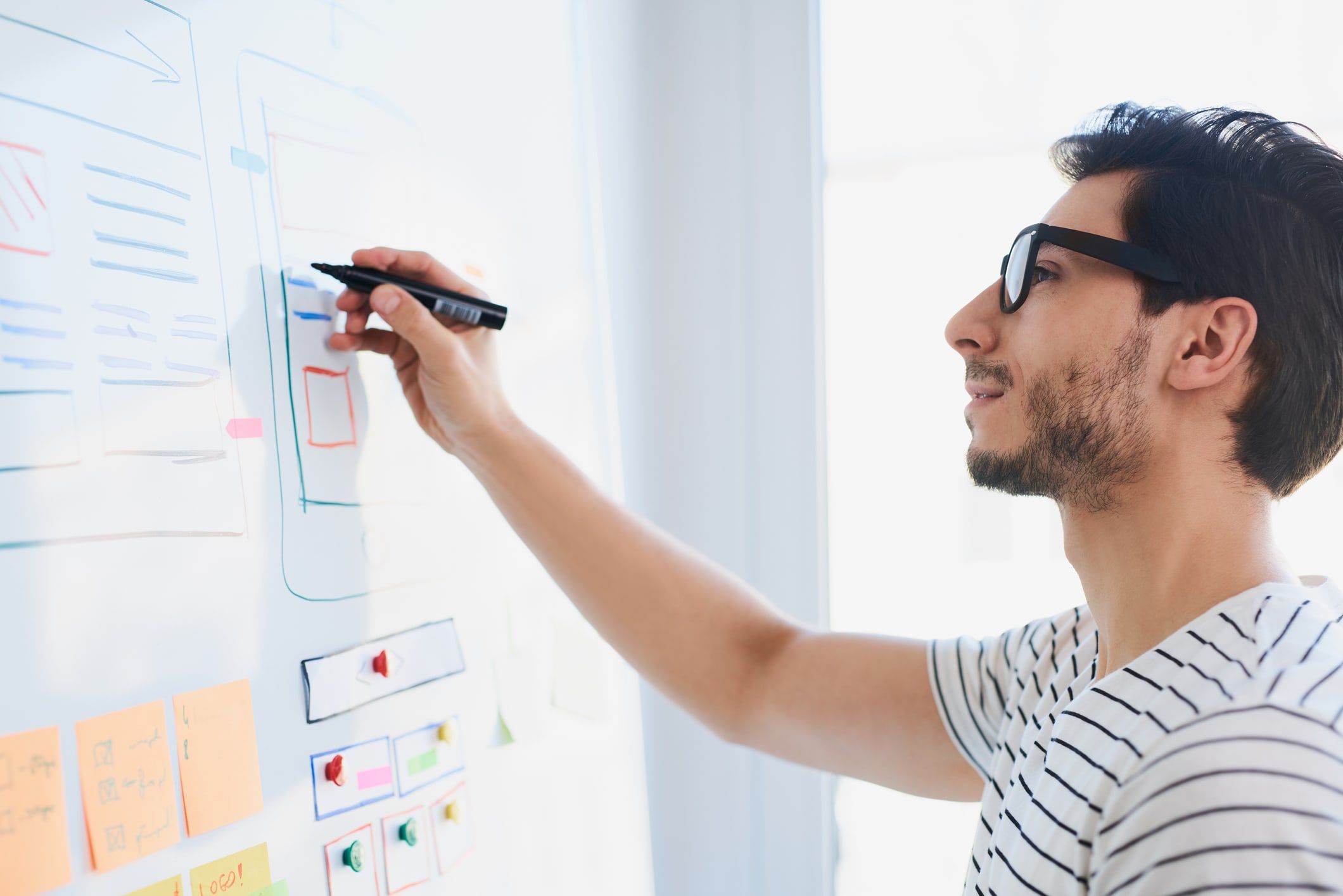 Jeune homme qui écrit sur un tableau blanc au travail