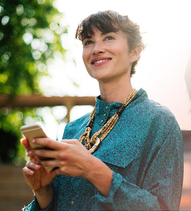 Femme qui regarde au loin avec un cellulaire entre les mains et notre outil de gestion des heures chômées et rémunérées