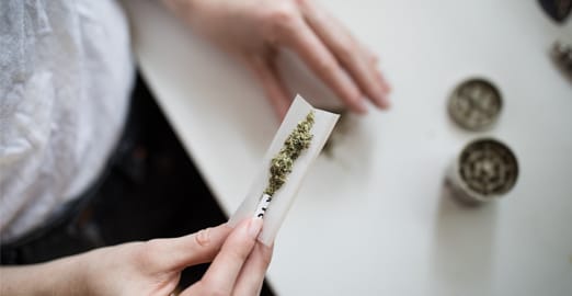 Personne en train de rouler un joint de cannabis sur son comptoir à la maison