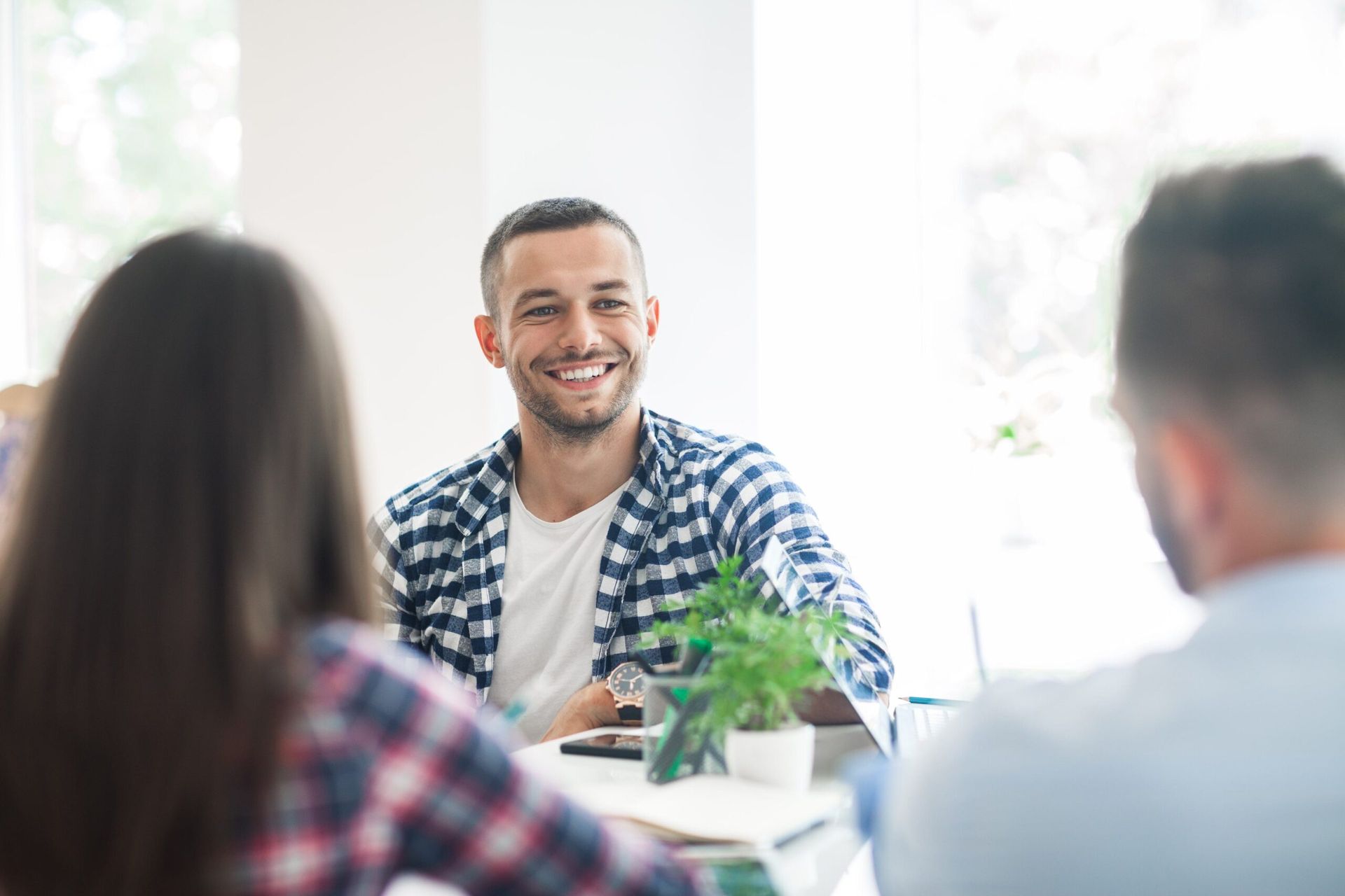 Jeune homme détendu et heureux qui se fait interviewer par un homme et une femme