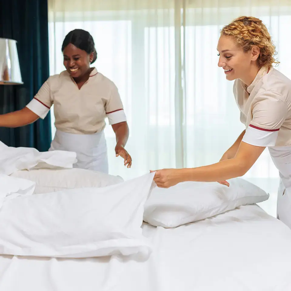Deux femmes de ménages préparant un lit d'hôtel.