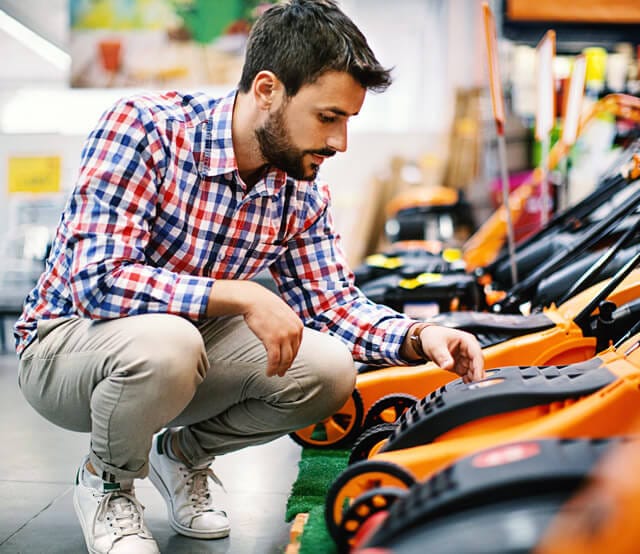 Homme considérant longuement l'achat d'une tondeuse à gazon