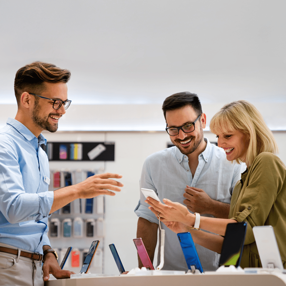 Photo of three employees looking at their phones and chatting, featured in a customer story about Bravad, an Agendrix customer.
