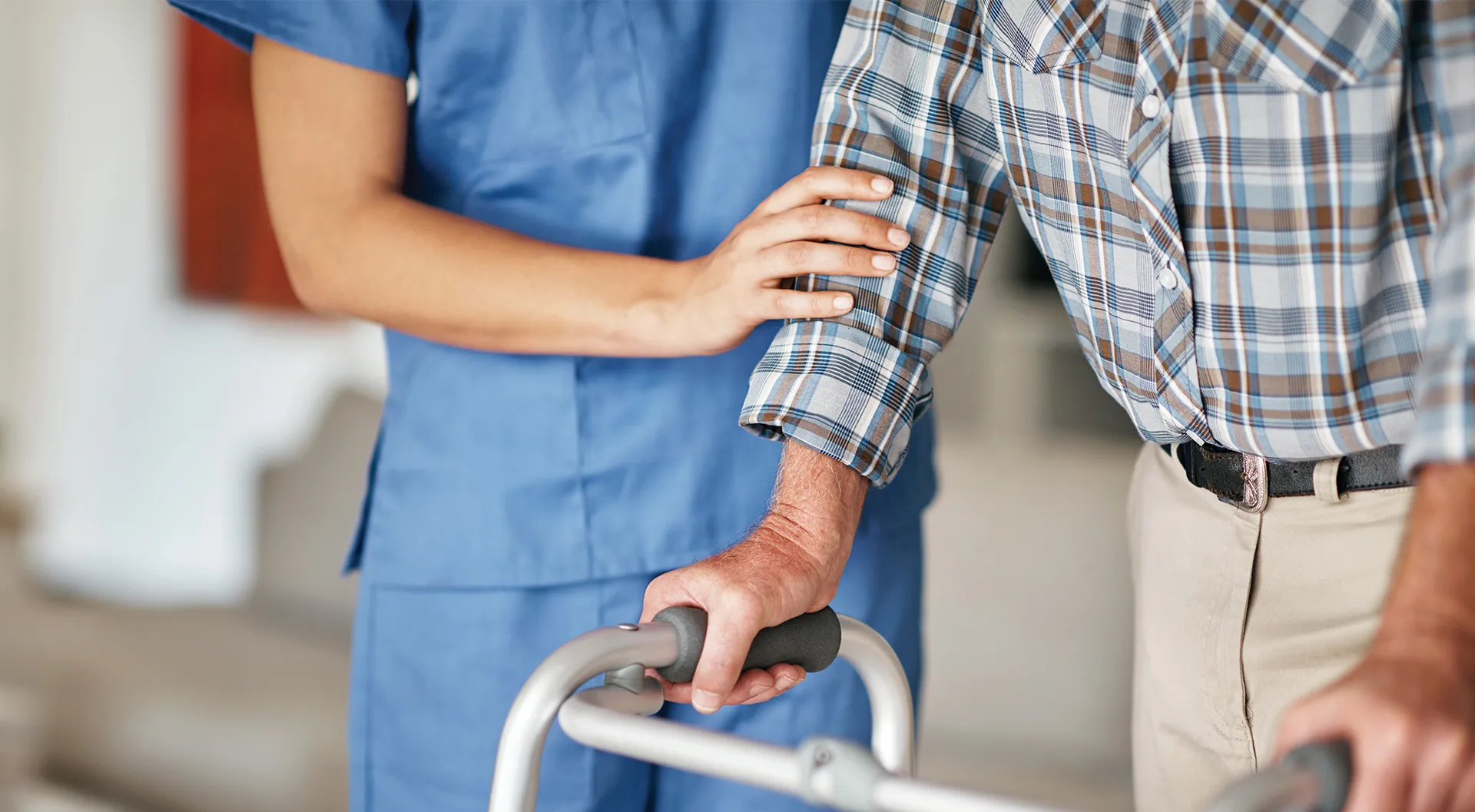 Hand of a care worker helping a patient to walk with a walker