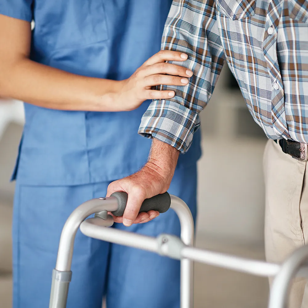 Hand of a care worker helping a patient to walk with a walker